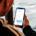 Mand tjekker varmepumpens status i app p� mobilen om bord p� b�den