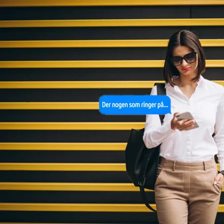 Kvinde ser d�rklokke-notifikation p� sin mobil foran en gul og sort baggrund