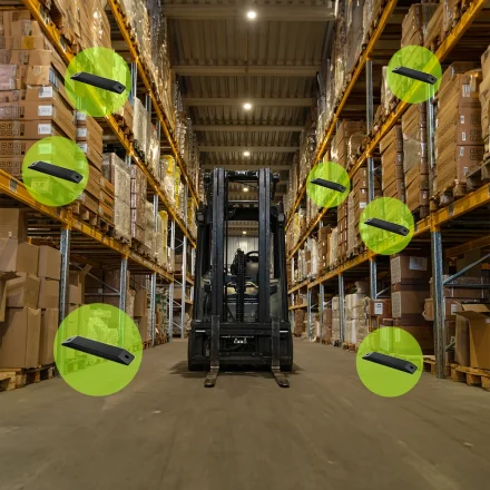Lagerhal med gaffeltruck og flere trackere fremh�vet p� h�jlagerreolerne